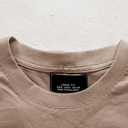 Label and collar of a cotton  beige stylish men's shirt on the white background. Fashionable details...