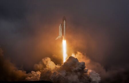 Rocket liftoff. Shuttle spaceship launch in the clouds sky. Spaceship begins the mission. Space shuttle taking off on a mission. Concept space travel to marsの写真素材