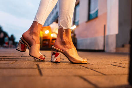 Elegant leather slippers shoes on female legs in the evening in the city, close-up.の写真素材