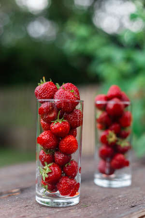 Fresh juicy strawberries in a glass on a wooden table in the garden. Natural Strawberry Juice Concept.の写真素材