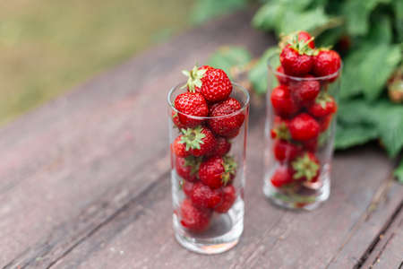 Tasty strawberries in a glass on a wooden table in the garden