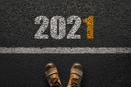 Male feet with boots on the asphalt with a white line and numbers for the new year 2021. The concept of a successful start. Step into the futureの写真素材