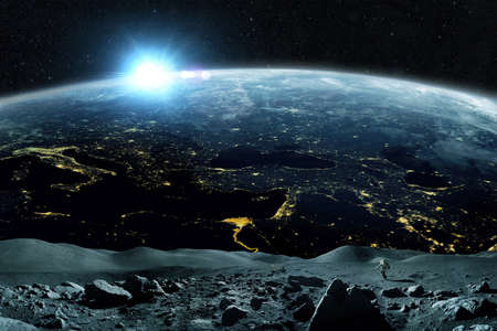 Space man walks on the moon in outer space with a amazing blue planet earth and sunset on the horizon. astronaut start performs the mission and explores the satellite asteroidの写真素材