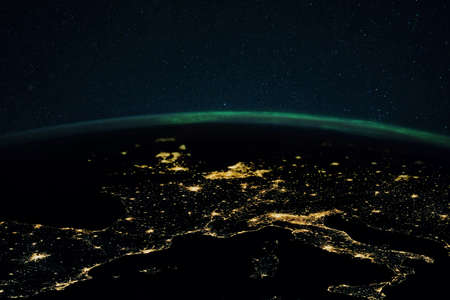 Night planet earth with the lights of megalopolis cities at night and the northern lights. Europe and the cities of Italy, France, Spain and Germany, view from space.の写真素材
