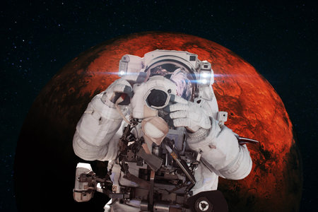 Astronaut photographer with a camera taking pictures against the background of the red planet Mars. Space mission conceptの写真素材