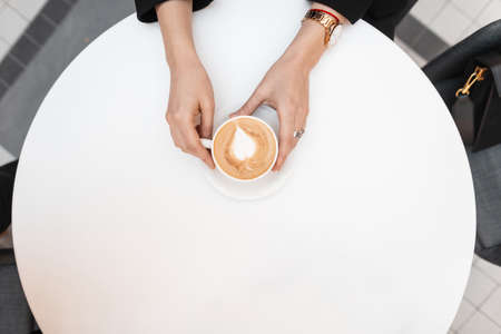 View from above on female hands with vintage a cup with delicious coffee with cream on the...