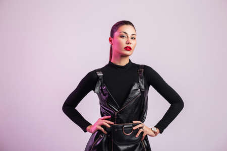 Fresh stylish portrait of pretty young woman with healthy clean skin with beautiful puffy red lips in fashionable black leather clothes with brown hair indoors. Chic sexy girl fashion model in the studioの写真素材