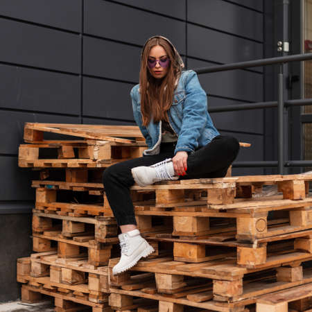 Stylish young pretty cool hipster woman in trendy jeans clothes in violet fashionable glasses in...