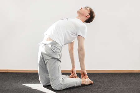 Young man trainer practicing yoga in fitness room. Sporty guy is doing stretching. Healthy lifestyle concept.の写真素材