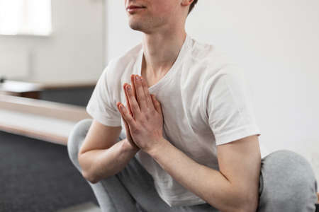 Young man yoga is training in the fitness studio. Concept of meditation and health lifestyle....