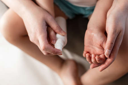 Mom processes the hands of her child from bacteria and viruses. antiseptic concept. child health careの写真素材