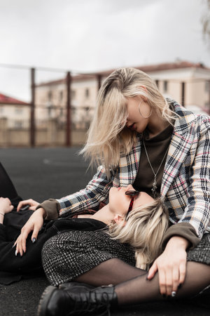 Fashion beautiful sisters in fashionable casual retro clothes sit and look at each other. Cute...