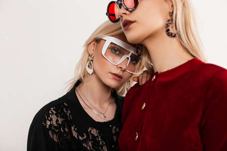 Retro portrait young sexy lesbians in fashionable red-black clothes in stylish glasses stand next to...