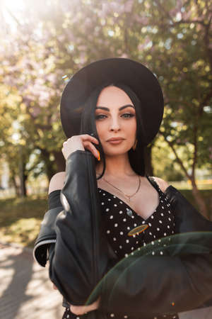 Sunny fresh portrait sexy woman in black beautiful dress in fashionable hat in vintage leather...