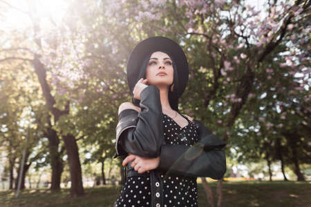 Elegant fine young woman model in fashionable black hat in stylish summer dress in vintage leather...