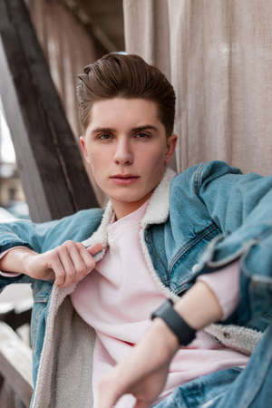 Street portrait good-looking young man with clean skin with stylish hairstyle in trendy blue denim...