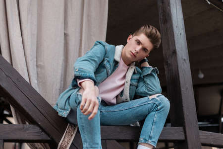 Handsome young man with trendy hairstyle in fashionable blue youth jeans clothes from new summer...