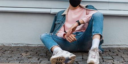 Urban young man with hairstyle in fashionable blue denim jacket in jeans in pink sweatshirt in...