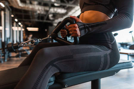 Sports girl athlete sitting and exercising in the gym, close-upの写真素材