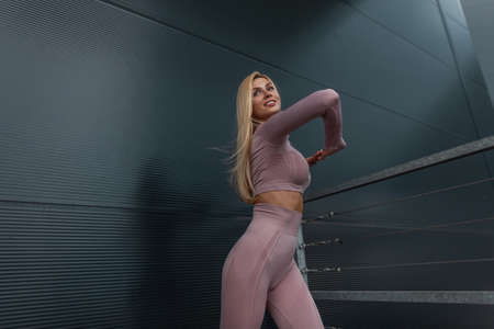 Fitness girl in fashionable sports clothes doing warm-up on the streetの写真素材