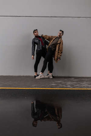 two fashionable beautiful urban model girls in a stylish leather jacket with a sweater and black...