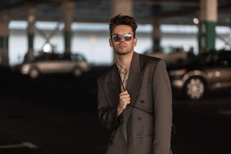 portrait of stylish businessman guy with hairstyle and stubble in fashionable business look outfit...
