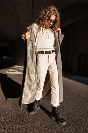 Young pretty girl with curly hair in fashionable clothes with a vintage coat, sunglasses, sweater,...