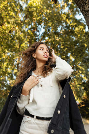 Fresh summer portrait of beautiful young woman with curly hairstyle in fashion fall denim clothes...
