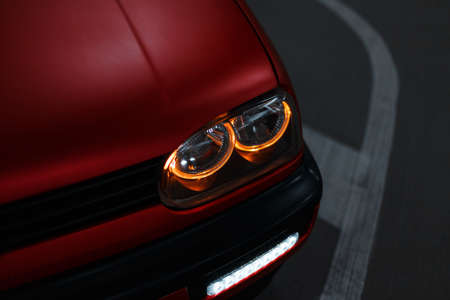 Beautiful classic red car with bright LED headlights in the night cityの写真素材