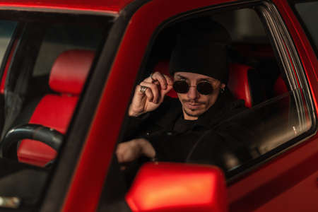 Young handsome guy driver look through sunglasses and drives a carの写真素材