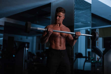 muscular young man with a muscular body exercising in the gym against a dark backgroundの写真素材