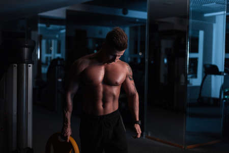 sport. Young athletic man doing workout in the dark. Muscular and strong guy exercising.の写真素材