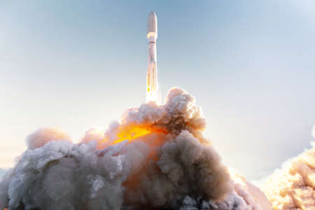 Space rocket takes off into space with clouds of smoke and fire against the clear blue sky. Successful start of the mission and will go into outer space. spaceship lift off conceptの写真素材