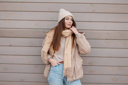 Happy beautiful young woman in fashionable outerwear with a vintage hat, scarf, knitted sweater,...