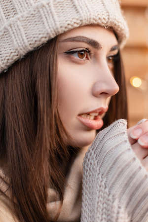 Emotional portrait of a pretty young woman with a cute face and brown eyes in fashionable knitted clothes with a hat and a sweater outdoorsの写真素材