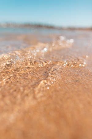 Close-up of water near the sea with yellow sand and blue sky. nice ocean view. macro nature water. Summer rest, vacation and travelの写真素材