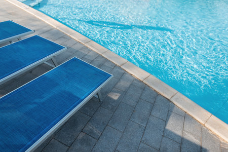 Beautiful blue swimming pool with sun loungers on a sunny warm summer day. Holidays and restの写真素材