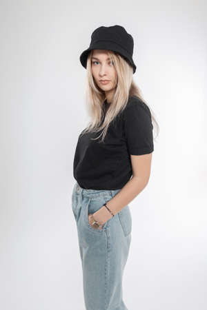 Stylish pretty young woman with blond hair in fashionable clothes with a black panama hat, t-shirts...