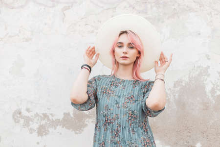 Comely elegant pretty young woman with pink hair in blue fashion beautiful dress straightens trendy...