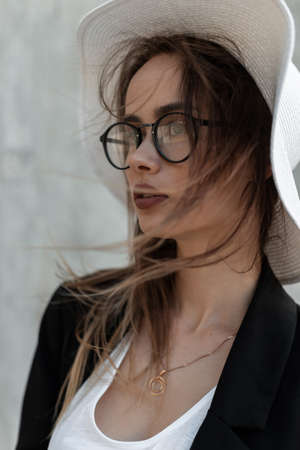 Fashion portrait young beautiful woman with pretty sexy lips in stylish beachwear in summer vintage hat in trendy glasses on gray background on street.の写真素材