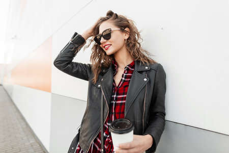 Beautiful happy woman with red lipstick with cute smile in sunglasses in fashionable red-black youth...