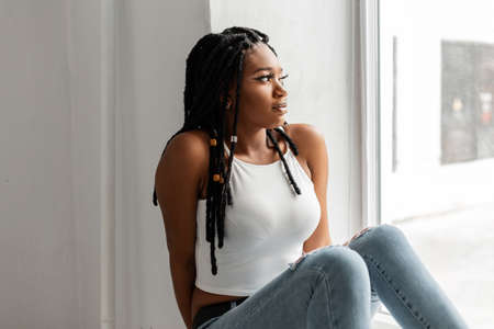 Pretty beautiful African American woman in fashion white top in stylish blue jeans with cool...