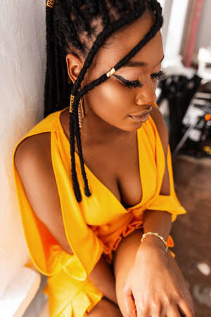 Fashion portrait of a beautiful stylish girl with dreadlocks hairstyle in a bright yellow dress in the studioの写真素材
