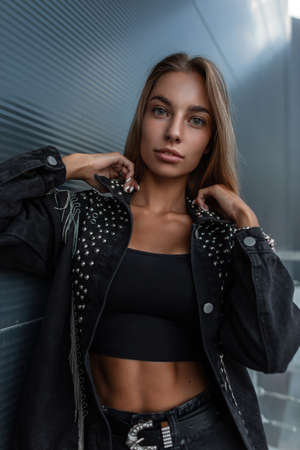 Fashion portrait of a beautiful young woman with a pretty face in black denim stylish clothes with...