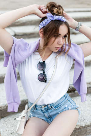 Pretty young woman with a bandana and sunglasses in a white t-shirt with a fashion sweatshirt in...