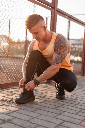 Handsome young stylish man with hairstyle and maya tattoo in trendy t-shirt, shorts and leggings...