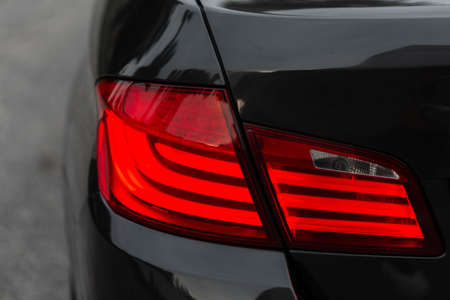Beautiful modern black car with rear stop lights, close-up. Red headlight LEDの写真素材