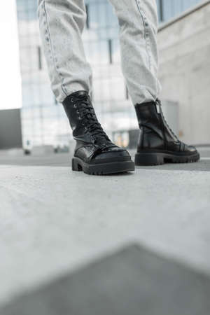 Trendy fashionable girl with leather fashion black shoes and jeans walks in the city, closeup....