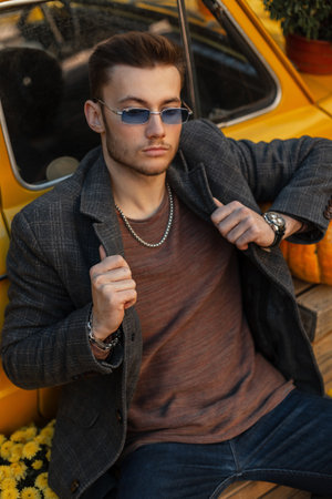Handsome trendy hipster guy with hairstyle and beard wearing fashion clothes with style coat,...