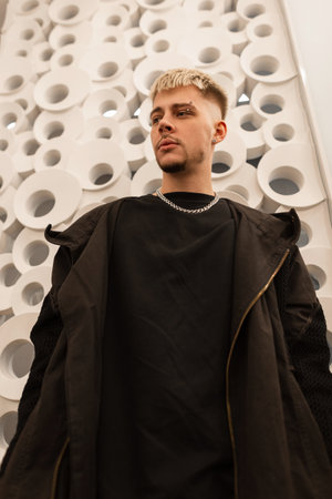 Fashion stylish handsome woman model in black fashionable clothes hoodie and t-shirt indoors near a wallの写真素材